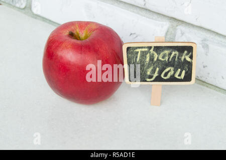 Apple mit einem Danke Inschrift auf einem Holzbrett schwarzer Hintergrund Stockfoto