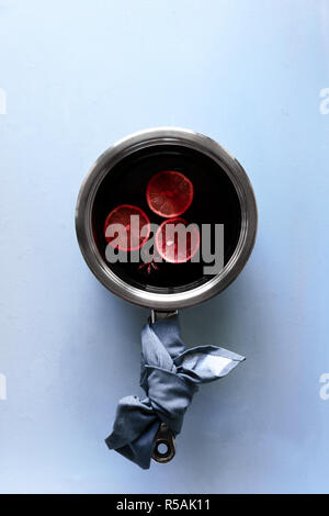 Glühwein in Aluminium Kasserolle auf grau Holztisch. Weihnachten und Winter wärmendes Getränk. Ansicht von oben. Flach Stockfoto