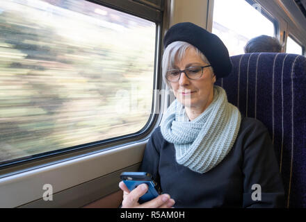 Ältere Frau auf eine Beschleunigung der Bahn, Mobiltelefon Stockfoto