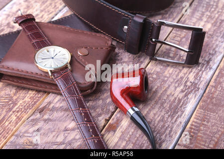 Set der Männer Zubehör für das Geschäft mit Leder Gürtel, Portemonnaie, Uhr und Rauchen Rohr auf einer hölzernen Hintergrund. Der Begriff Mode und Reisen Stockfoto