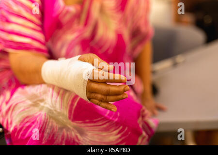 Ältere Frau mit Hand auf Verband zu Hause ruhenden verletzt. Stockfoto