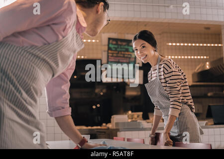 Schöne fröhliche Dunkelhaarige Kellnerin arbeiten mit Ihrem Freund Stockfoto