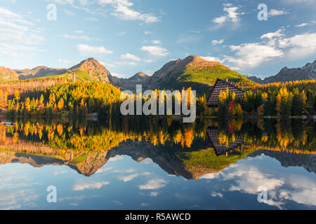 Malerischer herbst Blick auf den See Strbske Pleso in der hohen Tatra, Slowakei. Klares Wasser mit Reflexionen von orange Lärche und hohe Berge Stockfoto