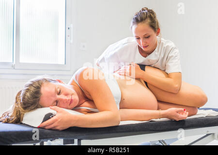Strukturelle Osteopathie Sitzung in einer schwangeren Frau. Stockfoto