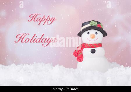 Schneemann Figur auf Schnee mit Happy Holidays Text auf einem farbigen Hintergrund Stockfoto