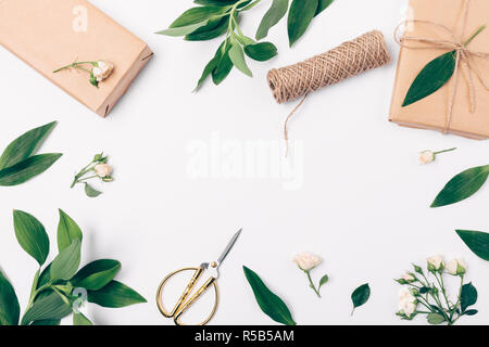 Festliche flach frame Zusammensetzung der Geschenkverpackung, Frischer Frühling Laub und Rosen, Ansicht von oben. Stockfoto
