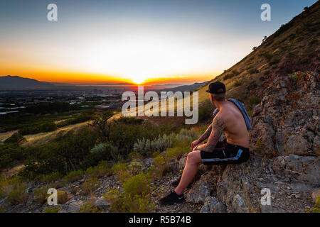 Tätowierten Mann beobachten die Sonne über Salt Lake City Utah eingestellt Stockfoto