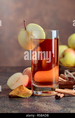 Glas Apfelsaft und Apfelwein mit saftigen Äpfel und Zimtstangen auf einem Küchentisch. Stockfoto