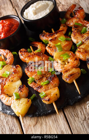 Köstliche Garnelen Kebab mit Ananas mit zwei Saucen in der Nähe serviert auf einem Holztisch. Vertikale Stockfoto