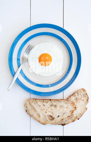 Gebratene Hühner Eier auf einem cornishware Platte mit Sauerteigbrot Stockfoto