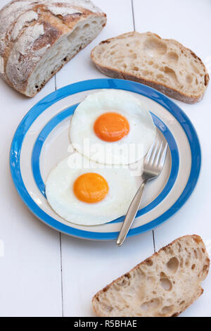 Gebratene Hühner Eier auf einem cornishware Platte mit Sauerteigbrot Stockfoto