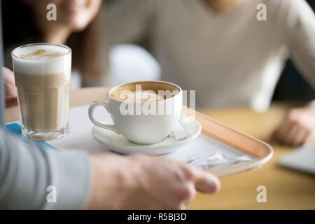 Nahaufnahme von Kellner Holding aromatischen Cappuccino und Latte auf Fach, um Cafe, Coffeeshop Arbeitnehmer geben heiße Getränke für die Besucher, Tassen wi Stockfoto