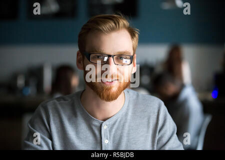 Portrait von lächelnden Rothaarige tausendjährigen Mann mit Kamera im Cafe oder Coffeeshop sitzen, glückliche junge Mann in Gläser für Bild posiert arbeiten Stockfoto