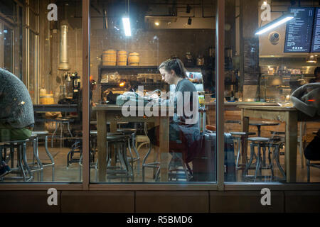 Kunden profitieren Sie von kostenlosem wi-fi in einem Café in Chelsea in New York am Dienstag, 20. November 2018. Das kostenlose Wi-fi und der gemeinschaftliche Tabellen regen die Nutzung der Coffee Shop als Arbeitsbereich. (© Richard B. Levine) Stockfoto