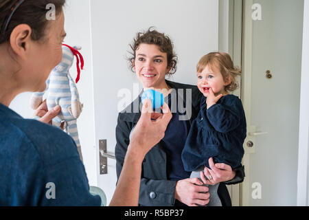 Eine Mutter nimmt ihr 16 Monate altes Baby Mädchen zu einem Baby caregiver. Stockfoto