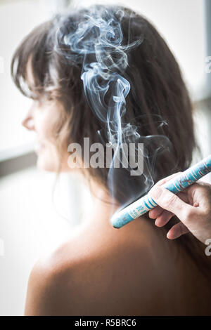Acupuncturist Holding eine glimmende Moxa Pol in der Nähe der Schulter des Patienten während einer Indirekte moxibustion Behandlung. Stockfoto