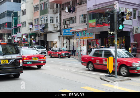 China, Hongkong, 2018-03-06: geschäftigen Stadtleben, Tag der Verkehr auf der Straße, eine Menge Auto und roten Taxi auf der Straße, auf dem Bürgersteig. Stockfoto