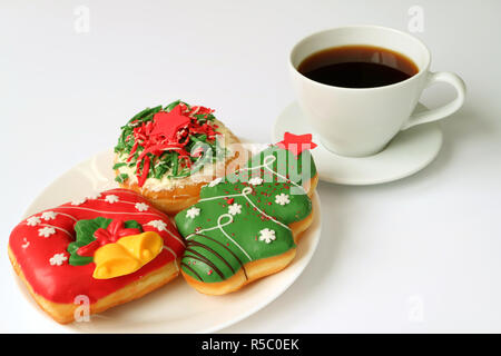 Halteplatte für Weihnachten dekoriert Süßigkeiten auf einem weißen Teller serviert auf einem weißen Tisch mit einer Tasse Kaffee Stockfoto