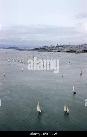 Panoramablick Blick Richtung Südosten von Segelboote Kreuzfahrt durch San Francisco Bucht in Richtung Pier 39 Während der Pazifik zwischen Yacht Association (PICYA) Eröffnung Tag der Bucht Parade, in San Francisco, Kalifornien, 30. April 1955. In der Ferne auf der linken Seite ist die San Francisco-Oakland Bay Bridge anschließen an Treasure Island. In der Mitte entlang der Küstenlinie ist Fisherman's Wharf und Marina District, mit Coit Turm und andere Orte im Hintergrund sichtbar. () Stockfoto