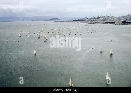 Panoramablick Blick Richtung Südosten von Segelboote Kreuzfahrt durch San Francisco Bucht in Richtung Pier 39 Während der Pazifik zwischen Yacht Association (PICYA) Eröffnung Tag der Bucht Parade, in San Francisco, Kalifornien, 30. April 1955. In der Abstand in der Mitte der San Francisco-Oakland Bay Bridge anschließen an Treasure Island. Auf der rechten Seite entlang der Küstenlinie ist Fisherman's Wharf und Marina District, mit Coit Turm und andere Orte im Hintergrund sichtbar. () Stockfoto