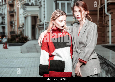 Hugging Freund. Große Rothaarige modische Frau ihre modischen blonde Freund umarmen Stockfoto