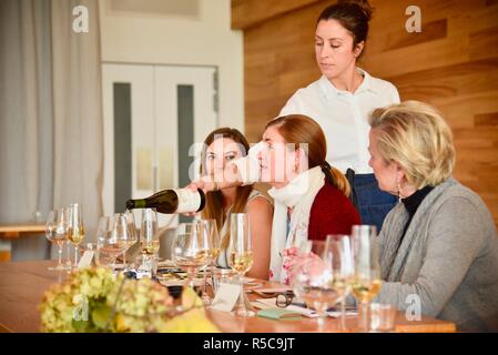 Attraktive Frau Kellnerin gießen Wein aus einer Flasche in Gläser in einem Restaurant Rezeption in Eureka Springs, Kalifornien, USA. Stockfoto