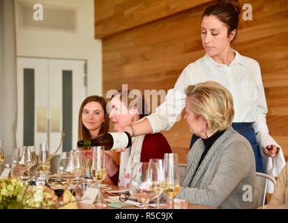 Attraktive Frau Kellnerin gießen Wein aus einer Flasche in Gläser in einem Restaurant Rezeption in Eureka Springs, Kalifornien, USA. Stockfoto