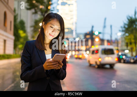 Business woman Nutzung Handy in Tokyo City bei Nacht Stockfoto