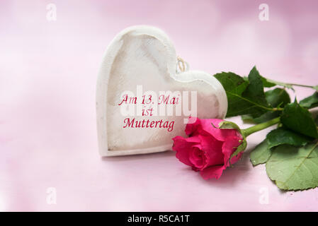 Herz aus Holz und eine Rose auf einem rosa Hintergrund, deutsche Text bin 13. Mai ist Muttertag, das bedeutet 13. Mai's Mutter ist Tag, ausgewählte konzentrieren Stockfoto