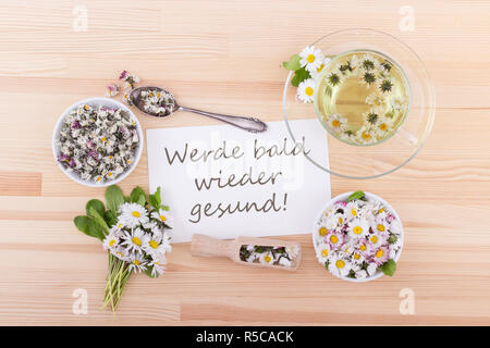 Karte für die Wiederherstellung mit Tee und Margeriten und deutscher Text: gute Besserung! Stockfoto