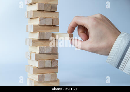 Unternehmer, die ersten oder letzten Block auf einen stabilen Turm von Holzblöcken. Konzept Foto von Planung, Risiken und strategische Planungen. Stockfoto