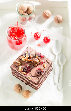 Schokoladenkuchen mit Kirschen und Walnüsse auf weißen Tisch Stockfoto