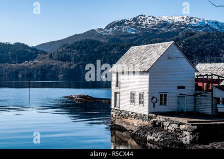 Eine typische norwegische Boat House auf die Fjorde und schneebedeckte Berge an einem schönen Frühlingstag. Norwegen Stockfoto