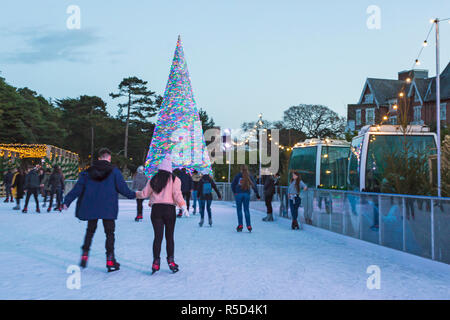 Bournemouth, Dorset, Großbritannien. 25 Nov, 2018. Besucher genießen Schlittschuhlaufen auf der Outdoor eislaufen Eisbahn in Bournemouth untere Gärten in Bournemouth im November, im Freien Eislaufbahn. Dahinter ist der Bournemouth Wunderland Baum, Teil der Bournemouth Weihnachtsbaum Wunderland, eine exemplarische Vorgehensweise Baum stehend 60 Fuß hoch und die Farbe ändert. Credit: Carolyn Jenkins/Alamy leben Nachrichten Stockfoto