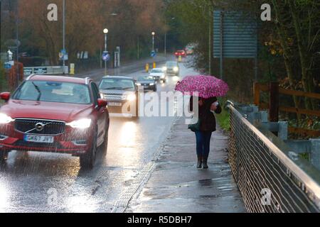 Ashford, Kent, Großbritannien. 01 Dez, 2018. Großbritannien: Das Wetter wechselhafter Witterung weiterhin als Beginn der meteorologische Winter mit heftigen Regenschauern beginnt: dieser Frau geht im strömenden Regen mit einem Regenschirm. © Paul Lawrenson 2018, Foto: Paul Lawrenson/Alamy leben Nachrichten Stockfoto