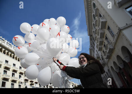 Thessaloniki, Griechenland. 1. Dez, 2018. Ein Mädchen hält Luftballons mit dem Red Ribbon Symbol auf Ihnen. Das Griechische Zentrum für die Prävention und die Kontrolle von Krankheiten organisiert eine informative Veranstaltung zum Welt-AIDS-Tag 2018, um das Bewusstsein für die AIDS-Pandemie durch die Ausbreitung der HIV-Infektion zu erhöhen. Credit: Giannis Papanikos/ZUMA Draht/Alamy leben Nachrichten Stockfoto