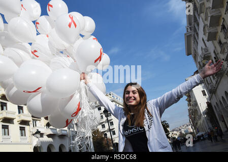 Thessaloniki, Griechenland. 1. Dez, 2018. Ein Mädchen hält Luftballons mit dem Red Ribbon Symbol auf Ihnen. Das Griechische Zentrum für die Prävention und die Kontrolle von Krankheiten organisiert eine informative Veranstaltung zum Welt-AIDS-Tag 2018, um das Bewusstsein für die AIDS-Pandemie durch die Ausbreitung der HIV-Infektion zu erhöhen. Credit: Giannis Papanikos/ZUMA Draht/Alamy leben Nachrichten Stockfoto