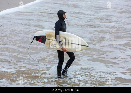 Bournemouth, Dorset, Großbritannien. 1. Dezember 2018. Surfer an der Küste der großen Wellen surfen am Strand von Bournemouth. Surfer Holding mit Surfbrett Surfboard zu Fuß ins Meer. Credit: Carolyn Jenkins/Alamy leben Nachrichten Stockfoto