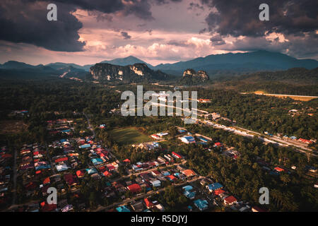 Luftaufnahme des Dorfes durch die Natur und die Berge in Malaysia bei Sonnenuntergang umgeben Stockfoto