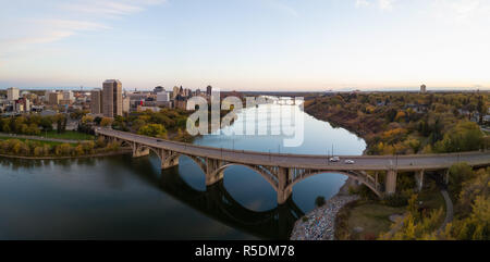 Antenne Panoramablick auf einer Brücke über den Saskatchewan River während einer lebhaften Sonnenaufgang in den Herbst zu gehen. In Saskatoon, SK, Kanada. Stockfoto