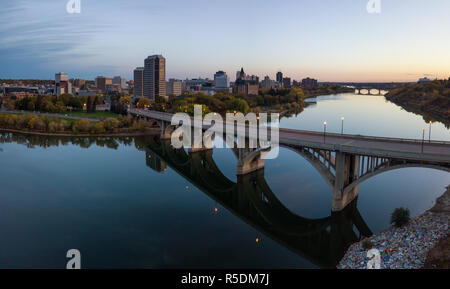 Antenne Panoramablick auf einer Brücke über den Saskatchewan River während einer lebhaften Sonnenaufgang in den Herbst zu gehen. In Saskatoon, SK, Kanada. Stockfoto