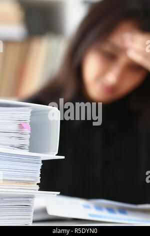 Müde und Frau sieht Dokumente bis zu stützen, die ihren Kopf mit ihren Händen erschöpft Stockfoto