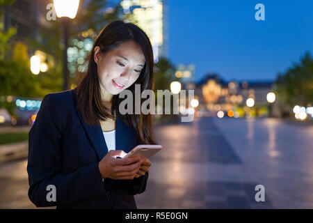 Geschäftsfrau Arbeiten am Handy in Tokyo City bei Nacht Stockfoto