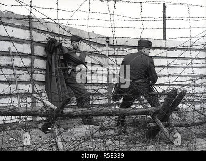 Ostdeutsche Soldaten vor der größten Mauer gebaut bis jetzt - die Arbeit Mannschaften errichtet fünf Meter hinter der alten, baufälligen und teilweise eingestürzten Wand, eine betonplatte neue, stabile Wand von einem Meter Breite, mit Zement ausgegossen. Es hat die Höhe von 2,50 Meter und ist damit die höchste Wand, die es gibt. 10/10/1962 Stockfoto