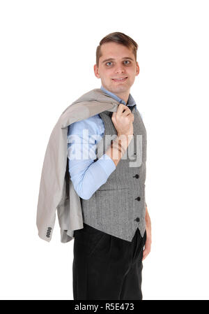 Ein hübscher junger Mann in einem grauen Weste und dunklen Hosen mit seinem grauen Jacke über seine Schulter, auf weißem Hintergrund Stockfoto