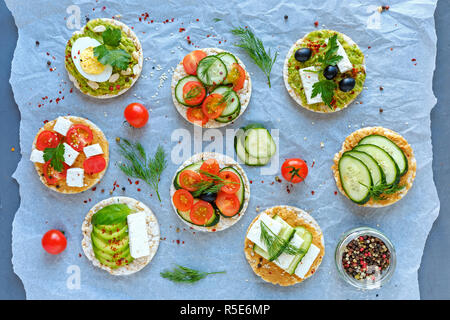 Gourmet Auswahl an frischen Vorspeisen oder Snacks auf zerknittertes Papier in einer Ansicht von oben mit frischem Gemüse, Käse und Kräuter auf Cracker angeordnet Stockfoto