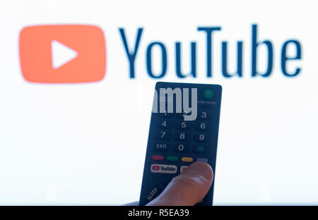 Ein Mann Punkte eine Fernbedienung auf ein intelligentes Fernsehen Anzeige der YouTube App in einem Schlafzimmer zu Hause in Großbritannien. November 2018. Stockfoto