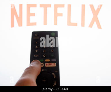 Ein Mann Punkte eine Fernbedienung auf ein intelligentes Fernsehen Anzeige der Netflix App in einem Schlafzimmer zu Hause in Großbritannien. November 2018. Stockfoto