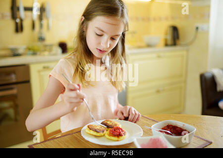 Süße kleine Mädchen, ihr Frühstück zu Hause genießen. Hübsches kind Pfannkuchen essen mit erdbeersauce vor der Schule. Gesunde Ernährung für Kinder. Stockfoto