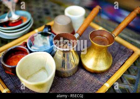 Kaffee in einer Kupfer cezve auf ein nettes Fach in der gemütlichen Küche gebraut. Bunte Keramik Tassen und frischem heißem Kaffee. Vorbereitung köstlichen Kaffee in CEZVE. Stockfoto